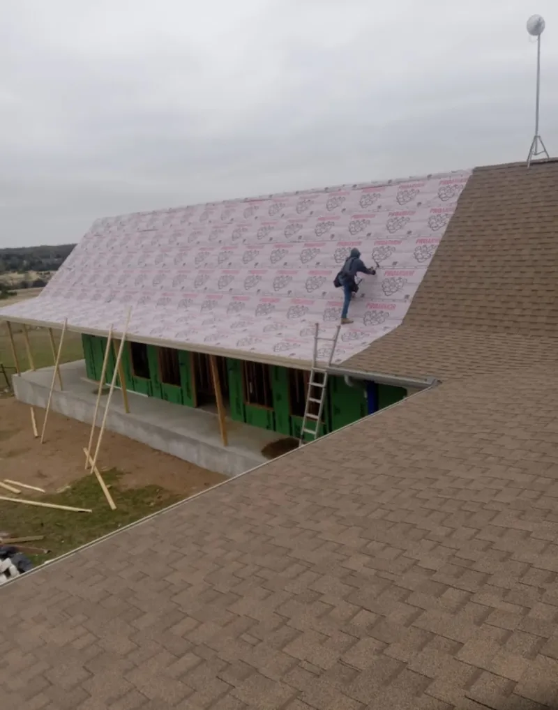 Worker preparing underlayment for a metal roof installation in Midland
